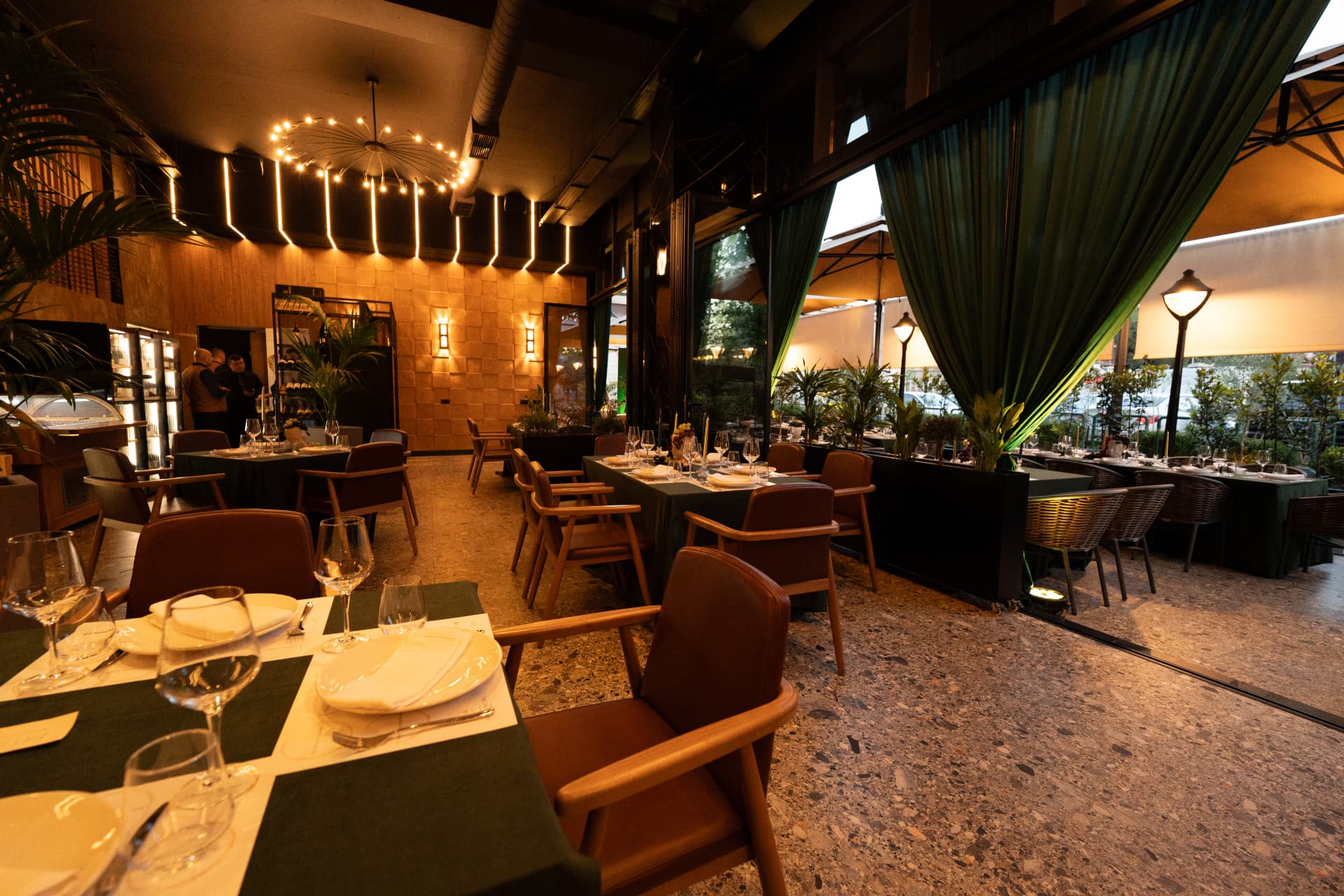 Salla e restorantit ASADOR me tavolina të shtruara dhe ndriçim të ngrohtë