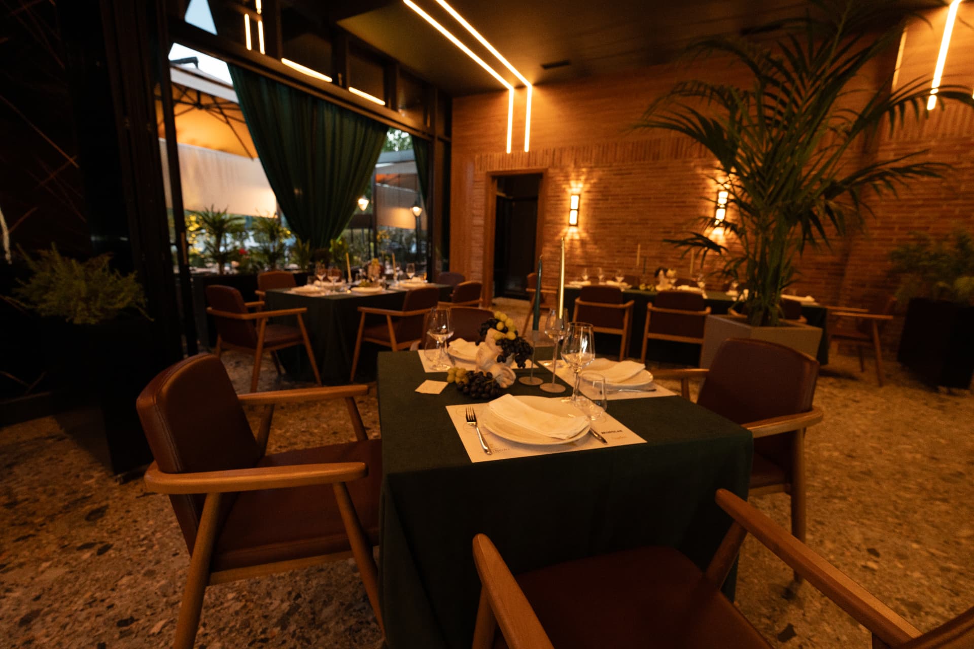 Tavolina me mbulesë të gjelbër dhe qirinj brenda restorantit ASADOR