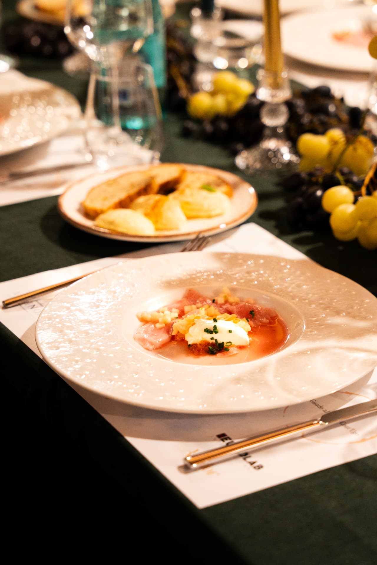 Carpaccio i servirur në tavolinën e mbrëmjes me rrush dhe qirinj