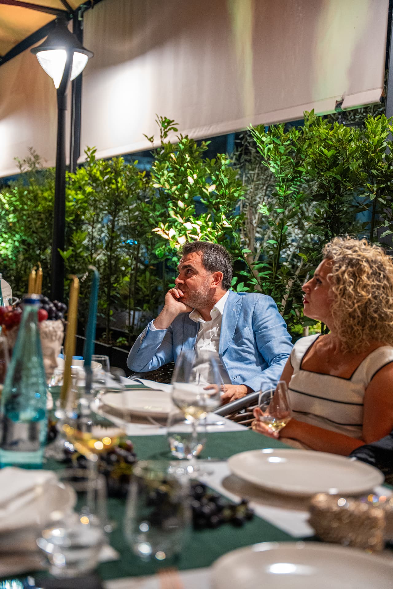 Mysafirë në tavolinën e gjatë të verandës nën dritën e mbrëmjes